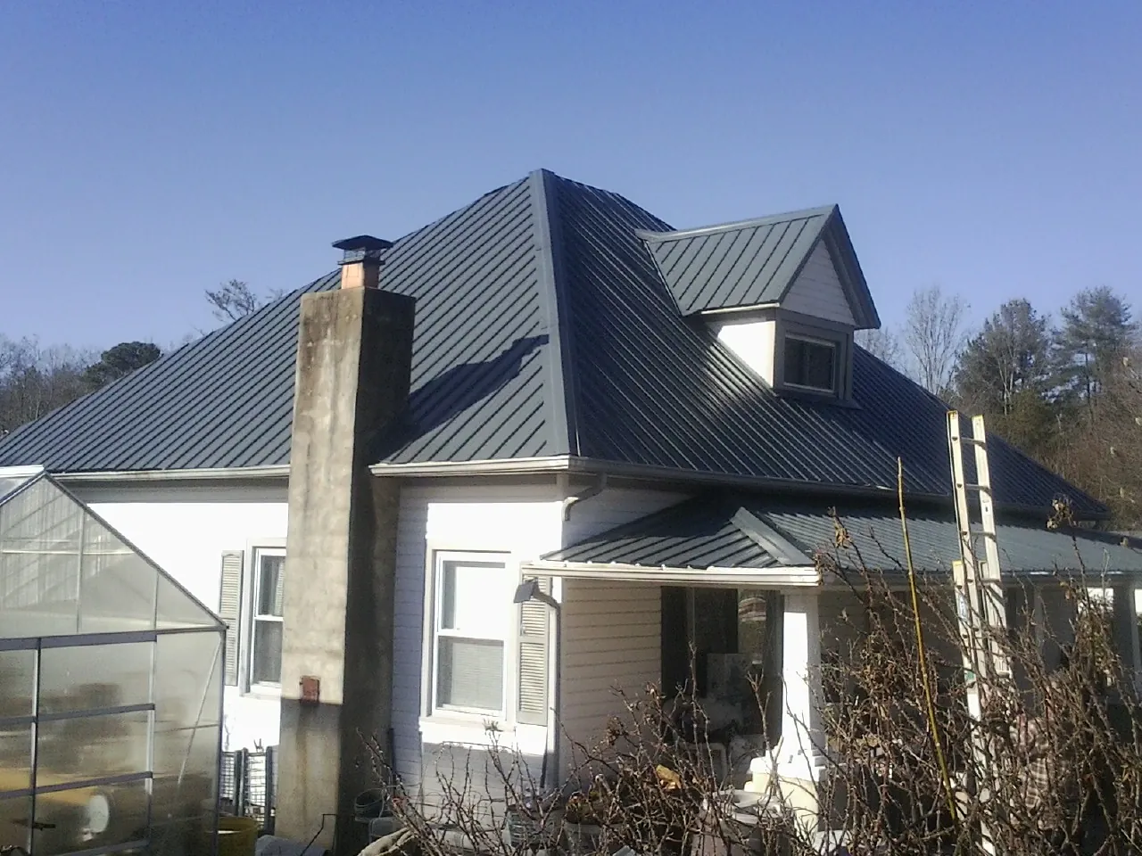 Dark blue standing seam metal roof on a white farmhouse with dormer — Slate & Tile Roof Repair by Roofing Brothers in Masontown