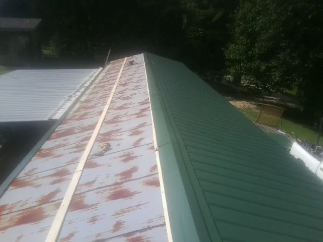 Old rusted panels beside newly installed green metal roofing — Wind Damage Roof Repair by Roofing Brothers in Masontown