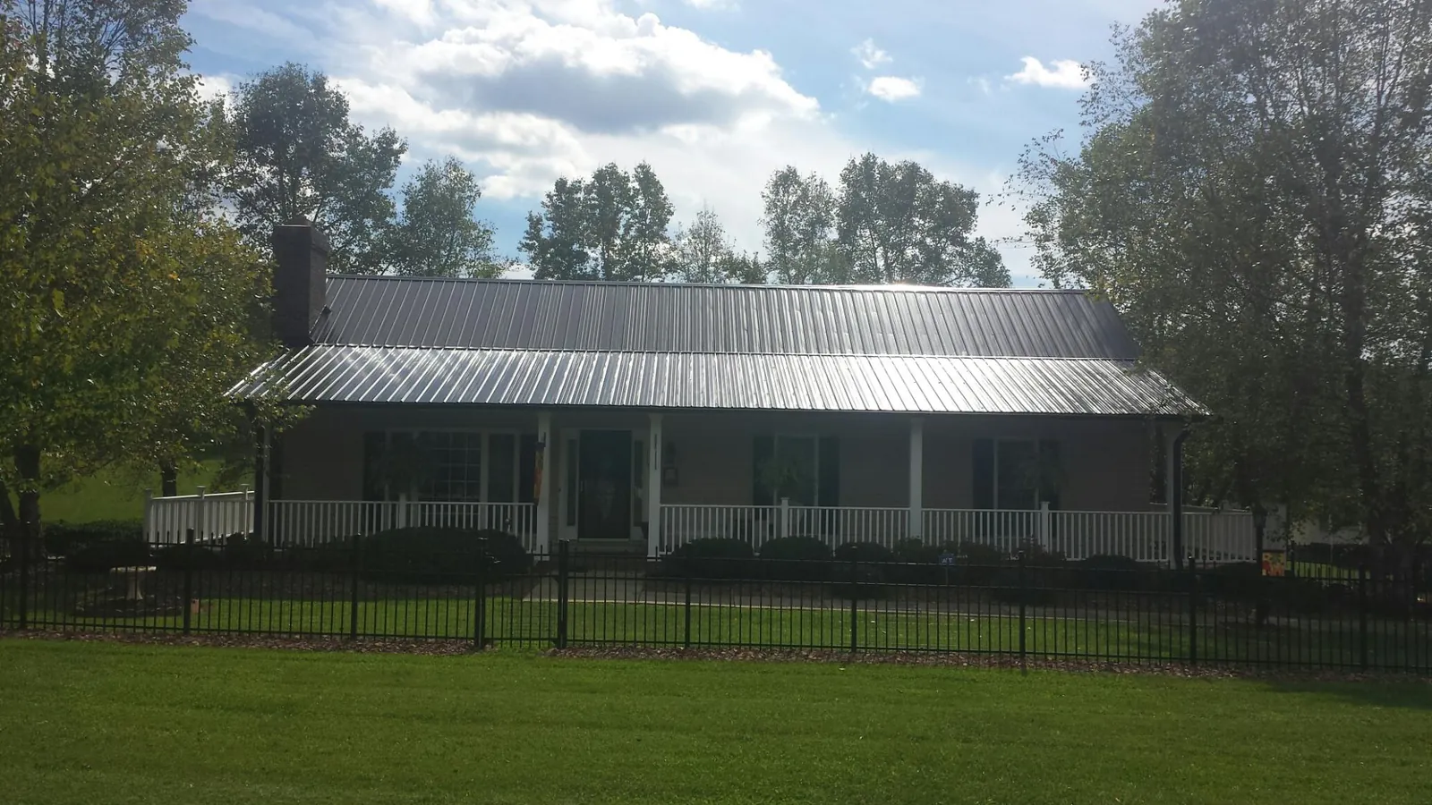 Gray metal roof on a brick ranch with a full width front porch — Gutter Guard Installation work by our crew in Masontown